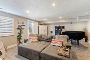 Living room featuring light wood finished floors, recessed lighting, and a textured ceiling