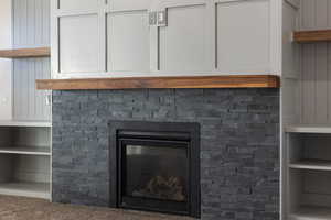 Detailed view of built in shelves, a glass covered fireplace, and carpet flooring