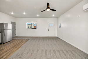 Unfurnished living room featuring ceiling fan, recessed lighting, light carpet, and a wall mounted AC
