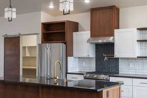 Kitchen with open shelves, white cabinetry, stainless steel appliances, dark stone counters, and recessed lighting