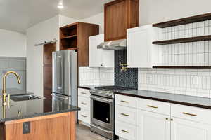 Kitchen featuring open shelves, stainless steel appliances, white cabinetry, a barn door, and light wood-style floors