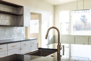 Kitchen with white cabinetry, open shelves, tasteful backsplash, and dark countertops