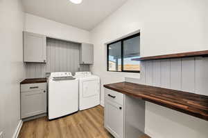 Laundry area with cabinet space, light wood-style floors, and independent washer and dryer
