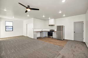 Kitchen featuring stainless steel appliances, white cabinets, dark colored carpet, open floor plan, and tasteful backsplash