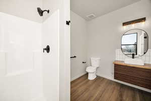 Full bathroom with vanity, a shower, wood finished floors, and tasteful backsplash