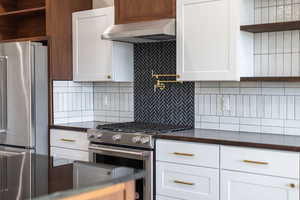 Kitchen with open shelves, stainless steel appliances, white cabinets, and extractor fan