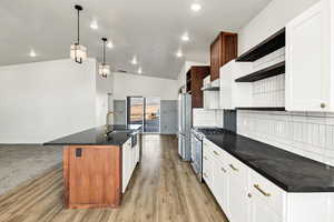 Kitchen with stainless steel appliances, a kitchen island with sink, hanging light fixtures, tasteful backsplash, and open shelves