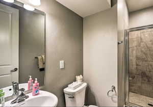 Full bathroom featuring a textured wall and a shower stall