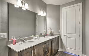 Bathroom featuring double vanity and dark wood-style floors