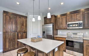 Kitchen featuring appliances with stainless steel finishes, a center island, a breakfast bar area, dark brown cabinetry, and recessed lighting