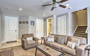 Living room featuring a ceiling fan, a textured ceiling, stairway, light tile patterned flooring, and recessed lighting