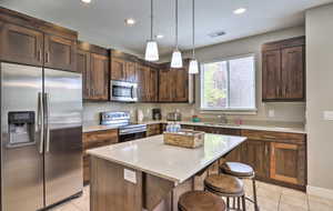 Kitchen with stainless steel appliances, pendant lighting, a kitchen breakfast bar, light tile patterned floors, and recessed lighting