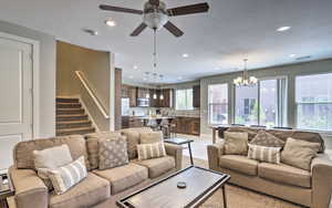 Living room featuring a chandelier, ceiling fan, stairway, recessed lighting, and a textured ceiling