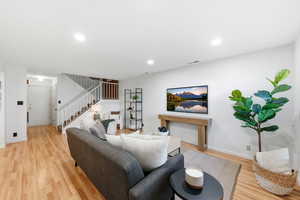 Living area featuring light wood finished floors, recessed lighting, and stairway
