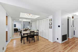 Dining area with light wood-style flooring, a chandelier, and electric panel