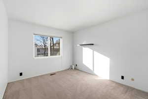 Unfurnished room featuring light carpet and baseboards