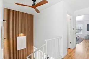 Corridor with an upstairs landing and light wood-style flooring