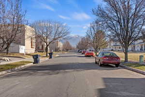 View of asphalt street featuring a residential view, curbs, and sidewalks