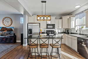Kitchen featuring black appliances, pendant lighting, backsplash, and a kitchen island