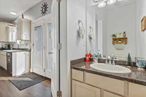 Bathroom featuring vanity, decorative backsplash, wood finished floors, and a closet