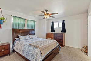 Carpeted bedroom with a ceiling fan and baseboards
