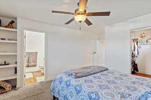 Carpeted bedroom with ceiling fan and connected bathroom