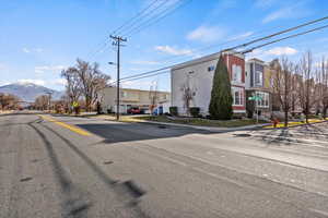 View of asphalt road with sidewalks, traffic signs, street lights, curbs, and a mountain view