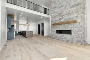 Unfurnished living room with a fireplace, light wood-style floors, recessed lighting, and a high ceiling