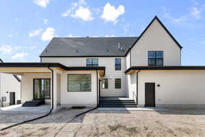 Rear view of house featuring a patio area, stucco siding, and roof with shingles