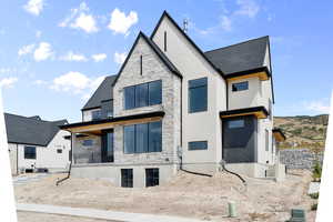 Rear view of house with stone siding, roof with shingles, stucco siding, and a porch