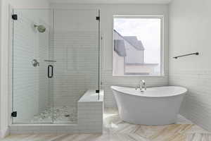 Full bathroom with a freestanding bath, a stall shower, tile walls, and wainscoting