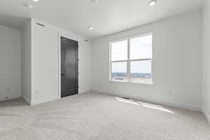 Unfurnished bedroom with light colored carpet and recessed lighting