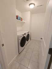 Washroom with a textured ceiling, light tile patterned floors, and washer and clothes dryer