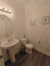Bathroom featuring dark wood-style flooring and wallpapered walls