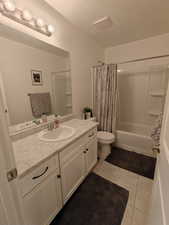 Full bathroom with vanity, shower / bath combo, and light tile patterned floors