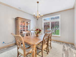 Dining space with crown molding, a chandelier, and light wood finished floors