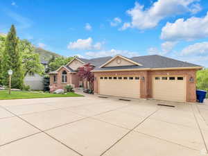 Ranch-style home with a shingled roof, an attached garage, concrete driveway, brick siding, and a front lawn