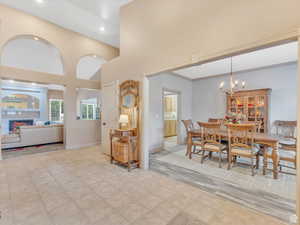 Dining space with a high ceiling, a lit fireplace, a chandelier, and recessed lighting