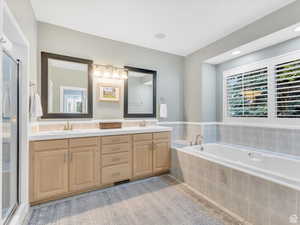 Full bathroom with double vanity, a stall shower, plenty of natural light, and a bath