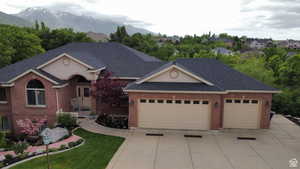 Ranch-style house featuring brick siding, an attached garage, driveway, a shingled roof, and a front lawn