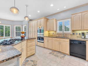 Kitchen featuring ornamental molding, dark stone countertops, black appliances, recessed lighting, and hanging light fixtures