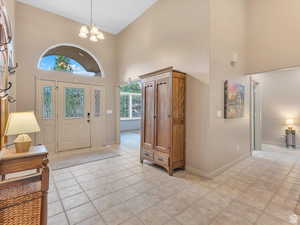 Foyer featuring a towering ceiling, a chandelier, and light tile patterned floors