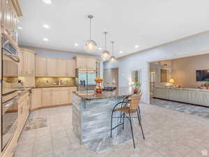 Kitchen with stainless steel appliances, open floor plan, a breakfast bar, dark stone counters, and pendant lighting