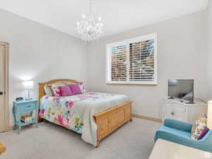 Carpeted bedroom with baseboards and a chandelier