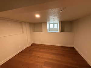 Below grade area featuring a textured ceiling, dark wood-type flooring, and recessed lighting