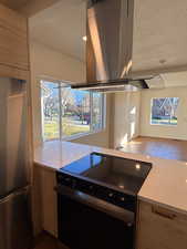 Kitchen featuring island exhaust hood, black electric range, freestanding refrigerator, a textured ceiling, and dark wood-style floors
