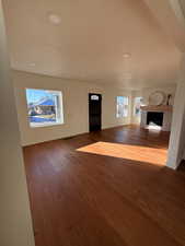 Unfurnished living room with a fireplace, dark wood-style floors, and a textured ceiling
