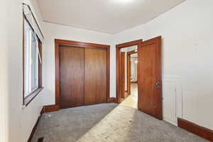Carpeted bedroom featuring a closet and baseboards