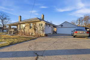 View of front of home featuring a chimney, an outdoor structure, and concrete driveway