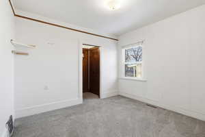 Empty room featuring light carpet and baseboards
